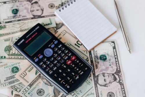 calculator on top of money next to notepad