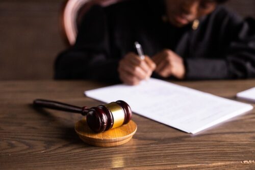 judge at desk signing document with gavel