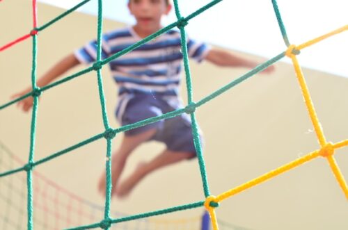child jumping behind a colorful net