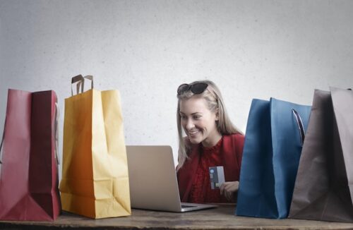 woman online shopping surrounded by bags