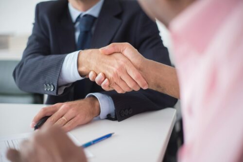 people shaking hands while sitting at table