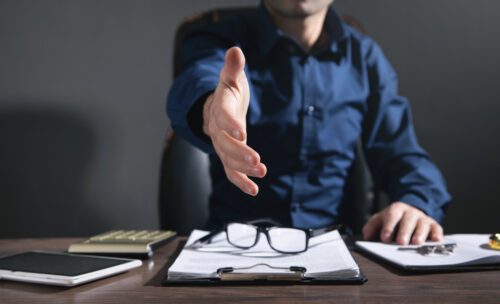 man offering hand for handshake at office.